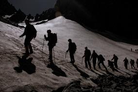 Silhouettes of the people, walking on the beautiful, snowy mountain peak