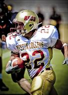 American football player in the shiny uniform and equipment, on the green field, on the competition