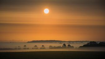 Beautiful, foggy landscape with the hills, at colorful, gradient sunrise with the clouds