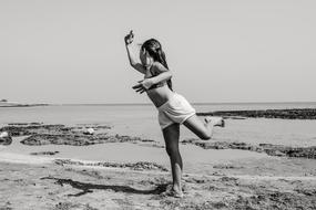 black and white photo of a girl dancing on the beach