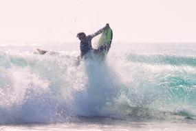 Surfer holding surfboard in foamy Waves