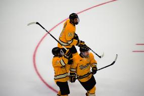 Hockey team players in orange, yellow and black uniform, on the ice