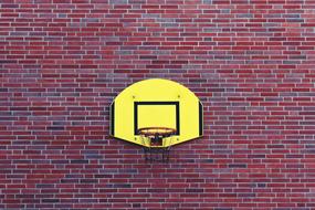 yellow basketball backboard on red brick wall