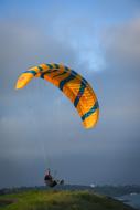 an athlete lands with a yellow-blue paraglider