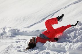 Woman in bright costume, laying on the beautiful, white snow on the mountain in winter