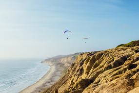 parachute flying over a rocky shore