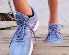 Close-up of the grey, red and white running shoes on the feet of a person, walking on the stairs