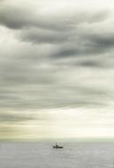 photo of a fishing boat in the middle of the lake against the backdrop of a cloudy sky