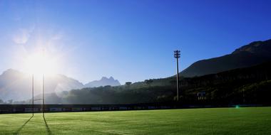 Beautiful landscape of the green rugby field, among the mountains in South Africa, at beautiful blue sky
