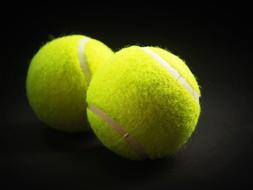 two tennis balls on black
