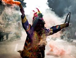 Carnival, person in colorful clothing with smoke bomb in hand