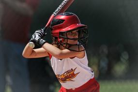 Softball batter girl, in the helmet, at blurred background