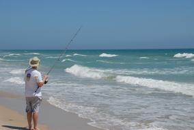 Fisherman Fishing on beach at Surf line