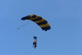 people are flying on a parachute against the blue sky