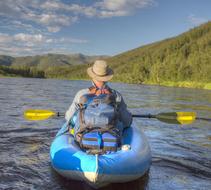 Back view of a person on the blue and white boat on Beaver Creek, among the beautiful landscapes of Alaska, USA