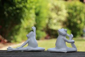 white ceramic figurines of frogs on a blurred background
