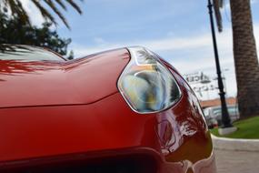 Close-up of the headlight of the shiny, red Ferrari car