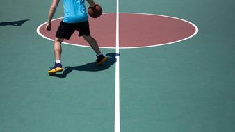 Man in Nike shoes, playing basketball on the green, red and white court