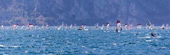 Windsurfing, lot of surfers on sea at rocky coastline