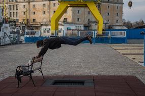 man is engaged in fitness near the bench on the street