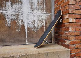 black skateboard against a brick wall