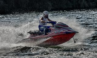 Person on the colorful jet ski on the water with white foam