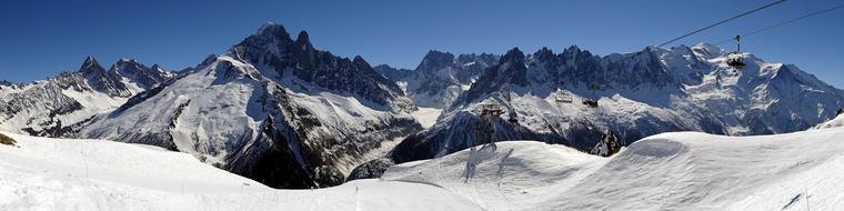 Beautiful panoramic view of the snowy Alps in light, under the blue sky