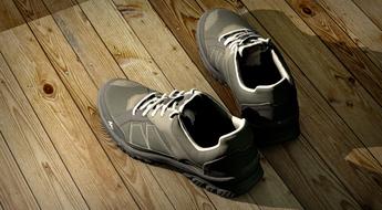 gray athletic shoes with shadow on a wooden floor