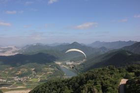 a man with a parachute is flying over the hills