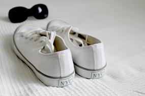 white sneakers sunglasses lie on the bed