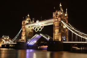 night photo of Tower Bridge with Olympic symbols in London