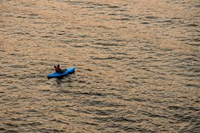 man in blue Kayak on Water at sunset