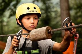 a boy in a helmet in a rope park