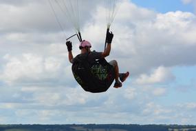 Back view of the paraglider, at blue sky with white clouds on background
