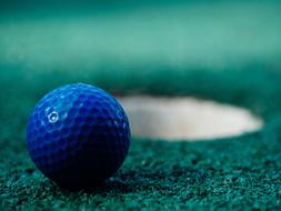 blue Golf Ball near the hole