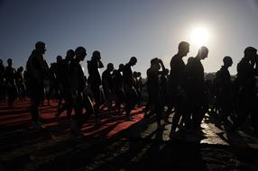 Silhouettes of the people on the triathlon race at background with Sun