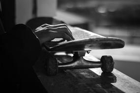 Black And White photo of Hand on Skateboard