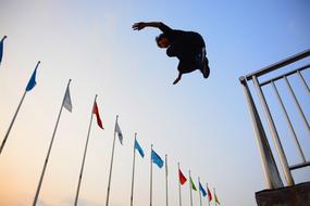 young boy in jump and colorful flags at evening Sky