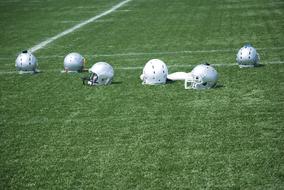 white american football helmets on green field