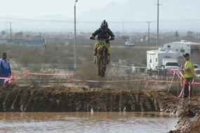 Rider, jumping above the water, on the motocross competition, on the landscape