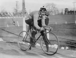 Black and white photo with the men on the road bike, near the field, in 1909