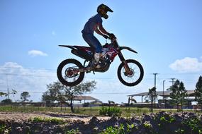 Man on the bike in jump, at beautiful background with green plants