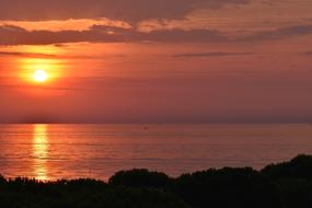 Beautiful landscape of the coast, near the water, with ripple, at colorful and beautiful sunrise in the clouds