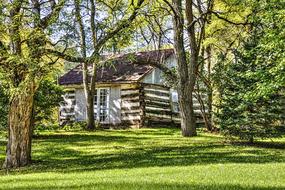 Beautiful log cabin, among the green field, and green and yellow trees, in the countryside in Ohio, USA