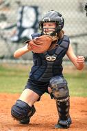 Softball catcher player on the field, with the fence, on the competition