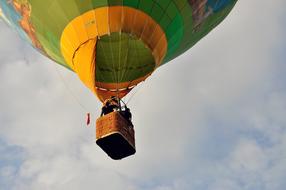 People in the flying, colorful hot air balloon, at background with the blue sky with clouds