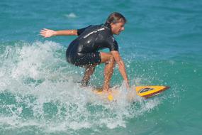 Surfer man in swimsuit, on the colorful surfboard, on the green and blue water