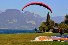 People, with the colorful parachutes for paragliding, among the colorful plants, near the beautiful Garda Lake in Italy