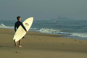 surfer with white board on the beach at sunset