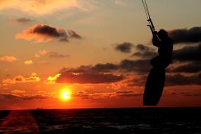 silhouette of a kitesurfer at dusk at sunset